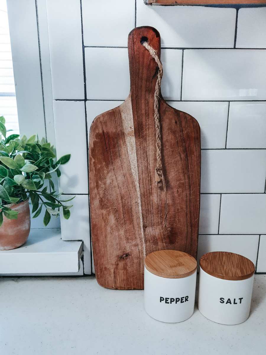 Wooden cutting board sitting in a white farmhouse kitchen