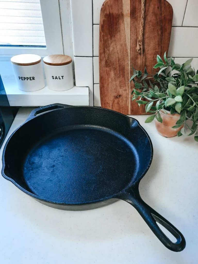 Cast iron skillet on white counter with wooden cutting board